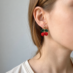 Micro crochet cherry earrings — close-up wearing view