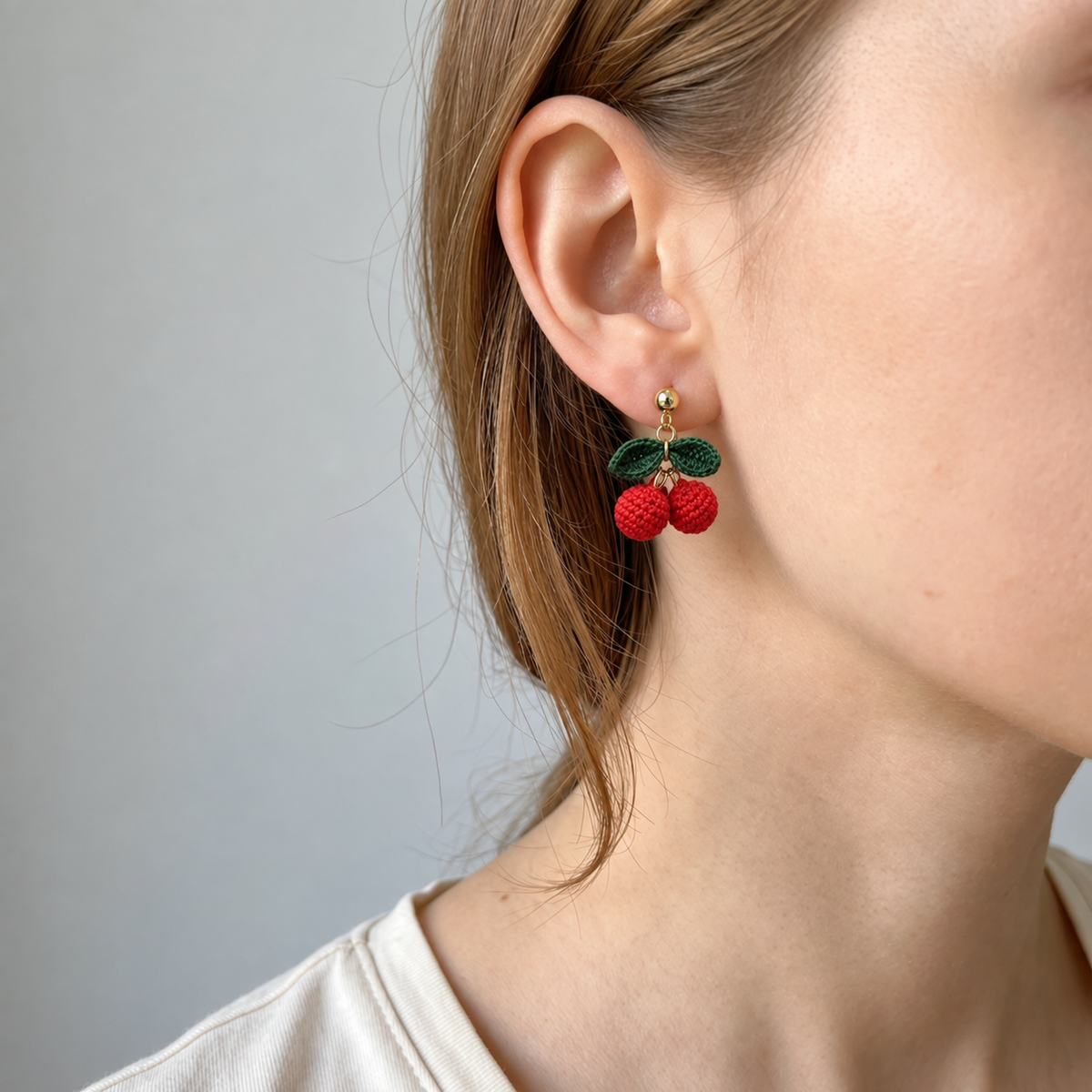 Micro crochet cherry earrings — close-up wearing view
