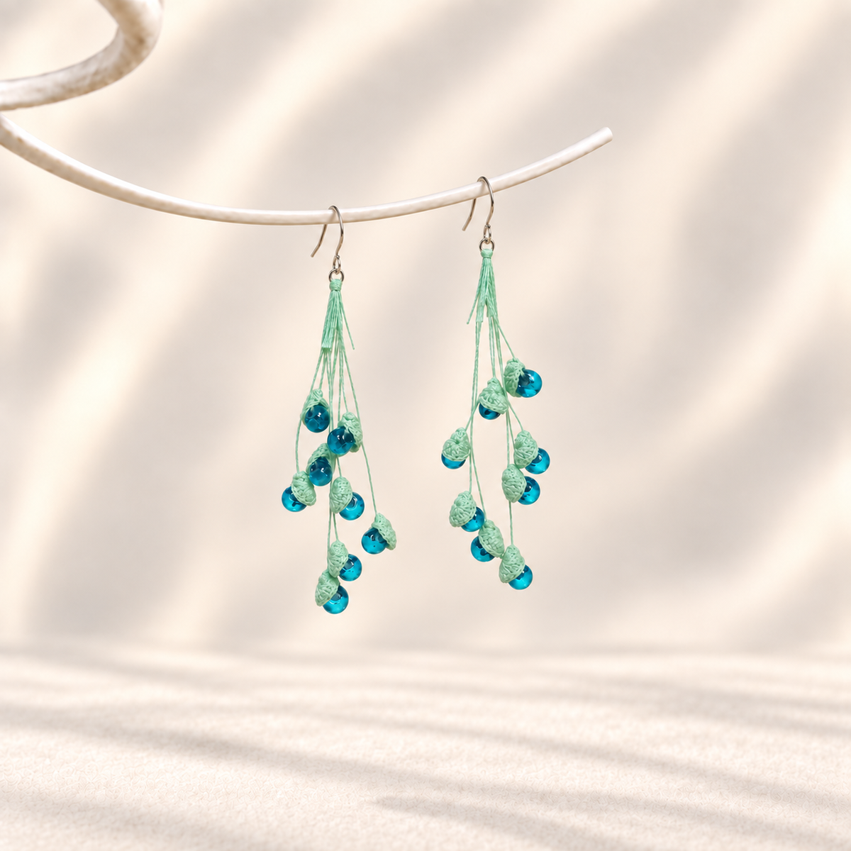 Petalore Blue lily of the valley micro crochet earrings — pair on an ivory display 