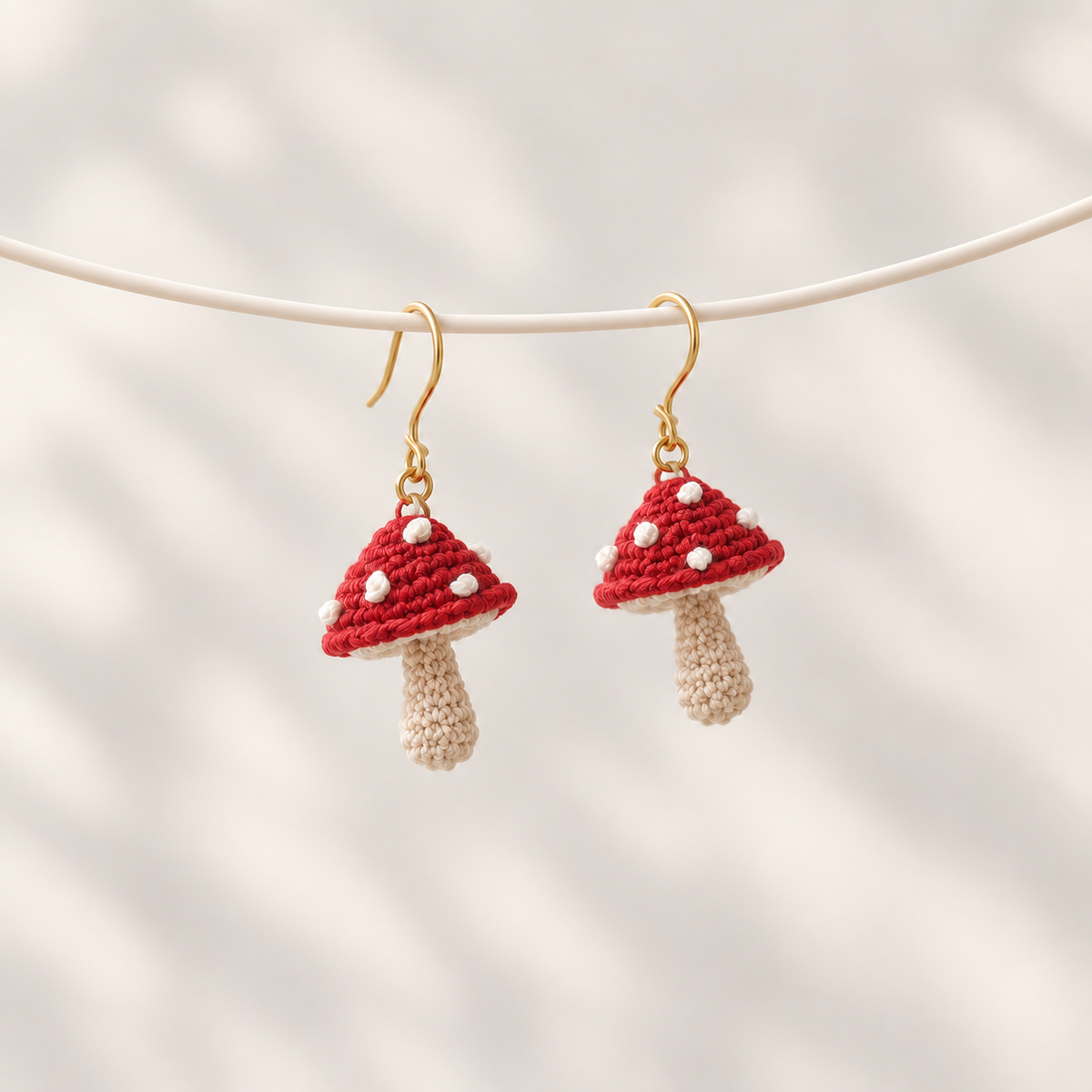 Petalore red micro crochet mushroom earrings — pair on an ivory display