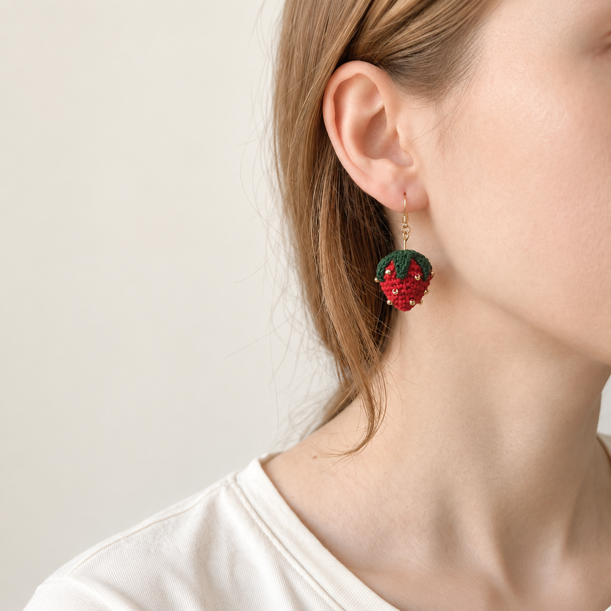Micro crochet strawberry earrings — close-up wearing view