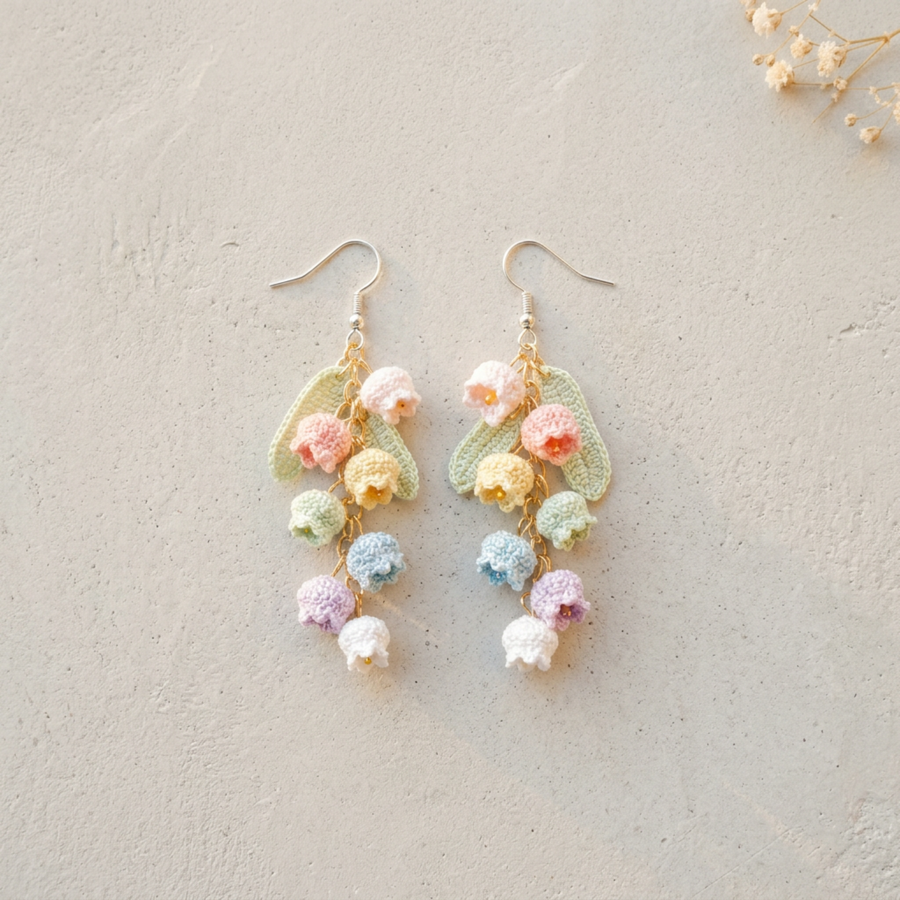 Micro Crochet Rainbow Bell Flower Earrings flat lay with dried flowers