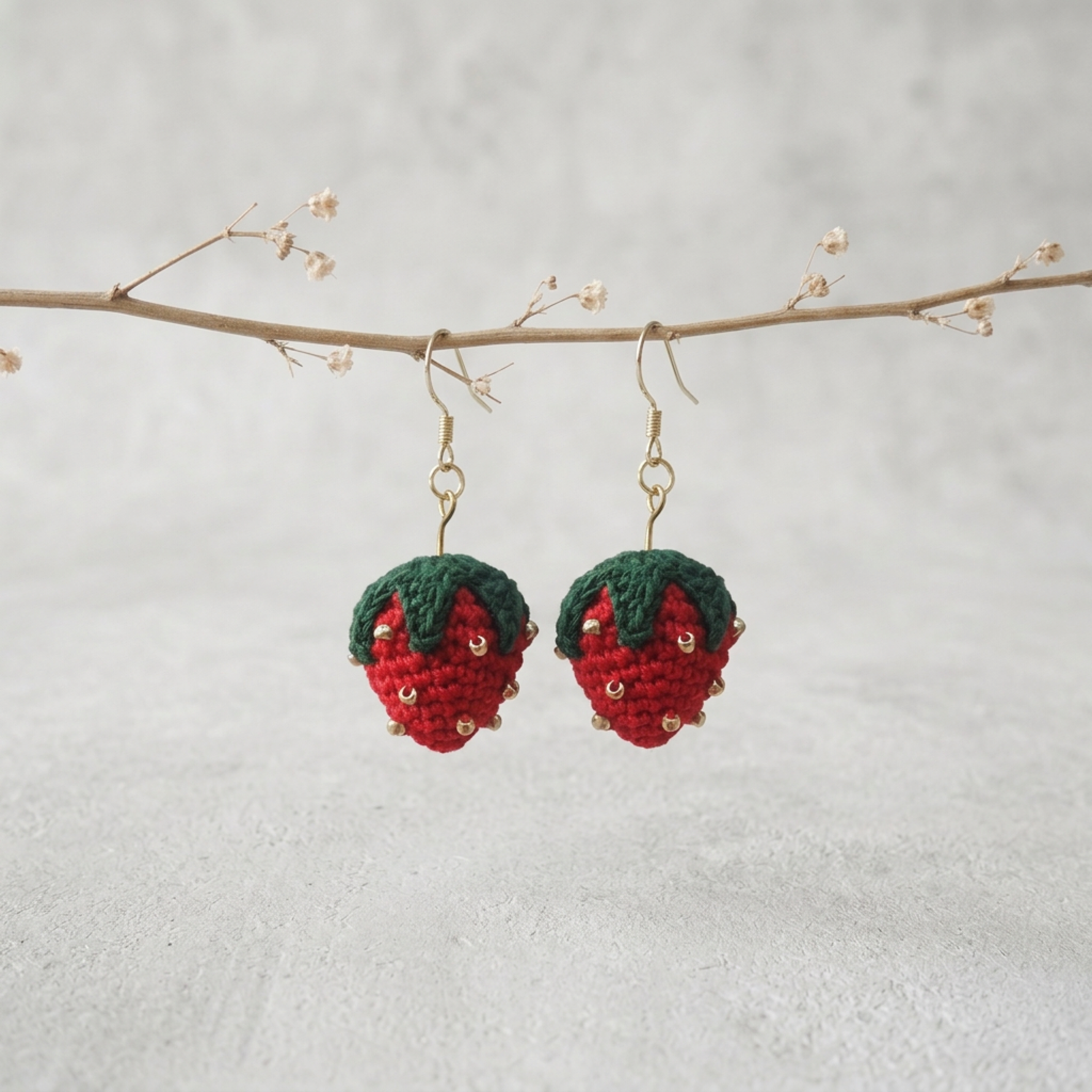 Micro Crochet Strawberry Earrings hanging from natural branch