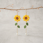 Golden yellow micro crochet sunflower earrings hanging from a branch