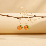 Micro Crochet Orange Earrings hanging from natural branch
